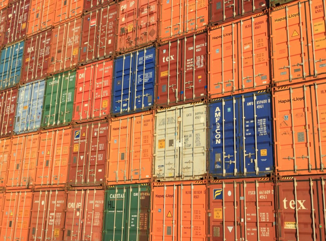 Colorful shipping containers stacked in a harbor, symbolizing global trade.